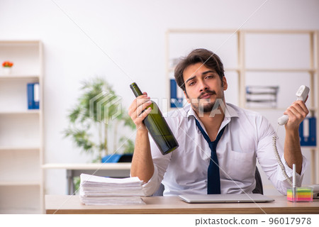 Young alcohol addicted employee sitting in the office 96017978