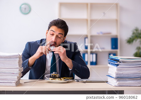 Young businessman employee eating alarm-clock 96018062