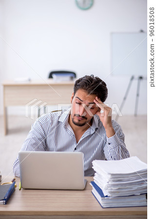 Young male employee and too much work in the office 96018508