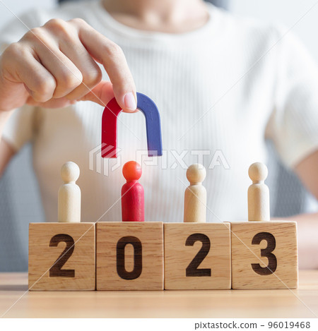 hand holding magnet and pulling man wooden figure from the crowd employee with 2023 Year block. Human resource management, Recruitment, Teamwork, strategy, toxic people and leadership Concepts 96019468