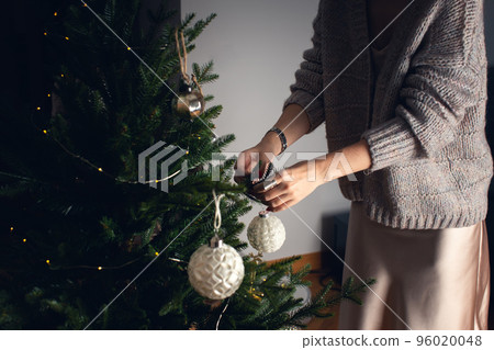 A girl decorates a Christmas tree for Christmas with balls. Front view. A girl decorates a Christmas tree for Christmas with balls. Front view. 96020048