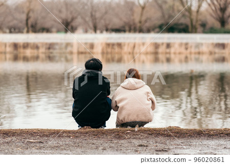 一對夫婦蹲在池塘邊擁抱的後視圖 96020861