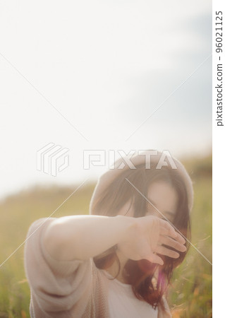 Photo of a woman standing in nature at sunset 96021125
