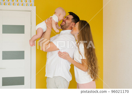 Happy parents hold their baby son in their arms at the top, look at him and smile 96021170