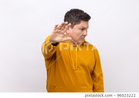 Portrait of middle aged man showing stop sign, standing with turning face, meaning caution to avoid danger or mistake, wearing urban style hoodie. Indoor studio shot isolated on white background. Portrait of middle aged man showing stop sign, standing with turning face, meaning caution to avoid danger or mistake, wearing urban style hoodie. Indoor studio shot isolated on white background. 96023222