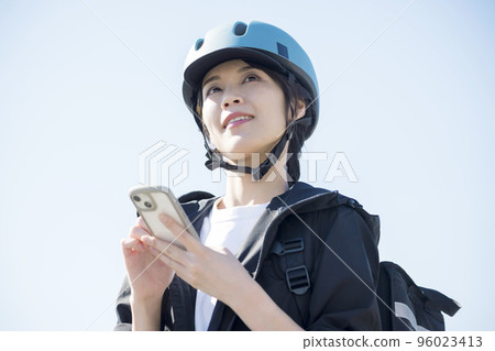 Food delivery image A delivery woman checking the destination on her smartphone Food delivery image A delivery woman checking the destination on her smartphone 96023413
