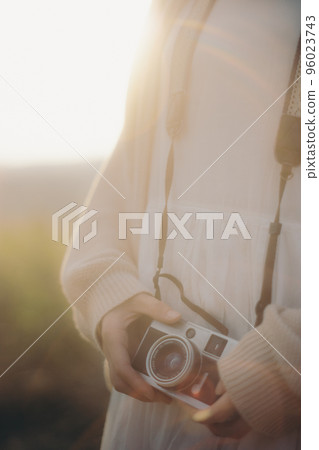 Photo of woman with camera in nature at sunset 96023743