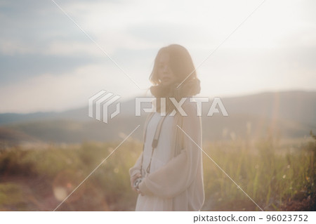 Photo of woman with camera in nature at sunset Photo of woman with camera in nature at sunset 96023752