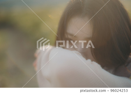 Photo of a woman standing in nature at sunset 96024253
