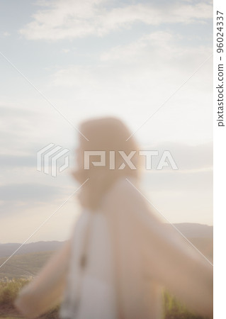 Photo of a woman standing in nature at sunset Photo of a woman standing in nature at sunset 96024337