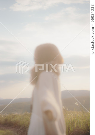 Photo of a woman standing in nature at sunset Photo of a woman standing in nature at sunset 96024338