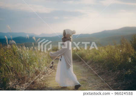 Photo of a woman standing in nature at sunset Photo of a woman standing in nature at sunset 96024588