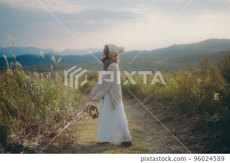 Photo of a woman standing in nature at sunset Photo of a woman standing in nature at sunset 96024589