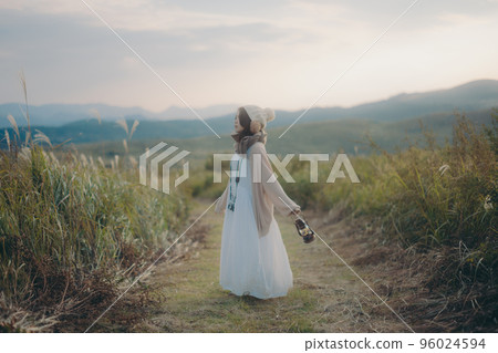 Photo of a woman standing in nature at sunset Photo of a woman standing in nature at sunset 96024594