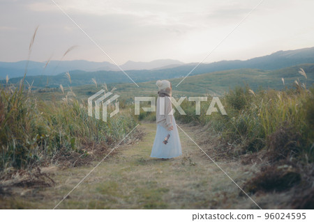 Photo of a woman standing in nature at sunset Photo of a woman standing in nature at sunset 96024595