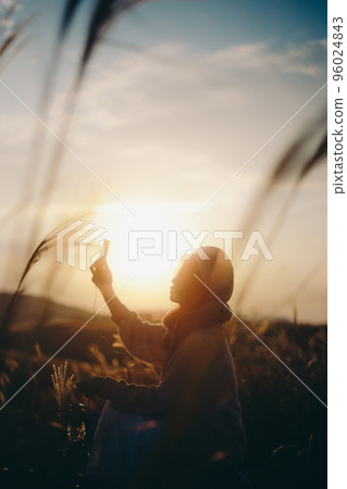 一個女人在日落時在大自然中聽音樂的照片 96024843