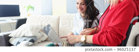 Smiling friends looking at photos on laptop, woman in wheelchair and disabled people Smiling friends looking at photos on laptop, woman in wheelchair and disabled people 96025137