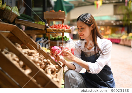 Image of female seller wearing apron arranging organic fruit on her stall at an open street market. Farmers market concept 96025188