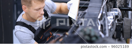 Concentrated male mechanic work with tool, fix damaged motorbike at workshop Concentrated male mechanic work with tool, fix damaged motorbike at workshop 96025189