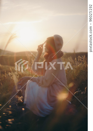 一個女人在日落時在大自然中聽音樂的照片 96025192