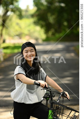 Portrait of smiling teenage girl with bike in the city park. People and outdoor activity concept Portrait of smiling teenage girl with bike in the city park. People and outdoor activity concept 96025308