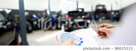Male worker writing machine diagnostic data in garage Male worker writing machine diagnostic data in garage 96025313