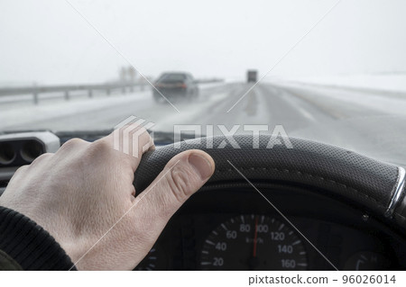 driver hand behind the wheel of a car driving on a slippery winter highway driver hand behind the wheel of a car driving on a slippery winter highway 96026014