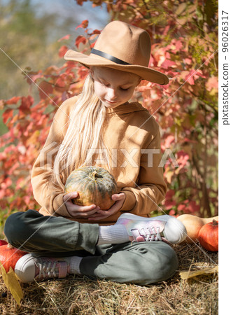 Girl in the hay with pumpkins Girl in the hay with pumpkins 96026317