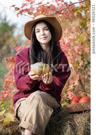 Happy young girl with pumpkin in autumn garden Happy young girl with pumpkin in autumn garden 96026321