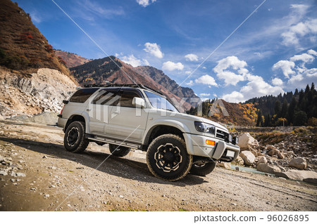 White off-road car in scenic mountains, copy space in sky 96026895