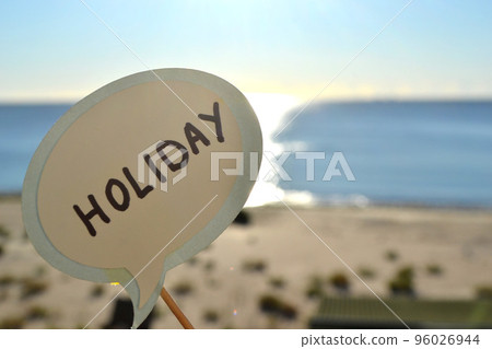Stick with paper speech bubble with words Holiday on background blue sea, sky, sandy beach on sunny summer day. Text-balloons with text from letters. Concept, symbol, sign vacation travel tourism rest Stick with paper speech bubble with words Holiday on background blue sea, sky, sandy beach on sunny summer day. Text-balloons with text from letters. Concept, symbol, sign vacation travel tourism rest 96026944