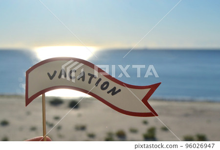 Stick with paper speech bubble with words Vacation on background sea, sky, sandy beach on a sunny summer day. Text-balloons with text from letters. Concept, symbol, sign vacation travel tourism rest. Stick with paper speech bubble with words Vacation on background sea, sky, sandy beach on a sunny summer day. Text-balloons with text from letters. Concept, symbol, sign vacation travel tourism rest. 96026947