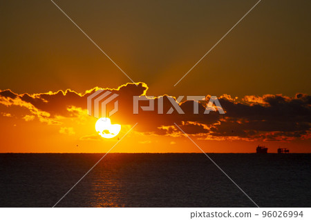 Dawn sun go behind cloud over sea horizon during dawn. Sunbeams, sun rays. Dawn sunrise dawning on sea. Black silhouettes of sea and clouds. Sky sea landscape. Seascape Fast moving clouds 96026994