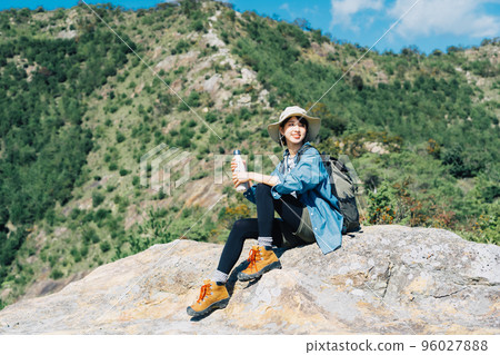 Woman drinking water on the mountain 96027888