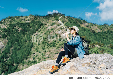 Woman drinking water on the mountain 96027890