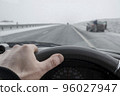 view of the driver hand behind the wheel of a car that passes by a stopped car 96027947