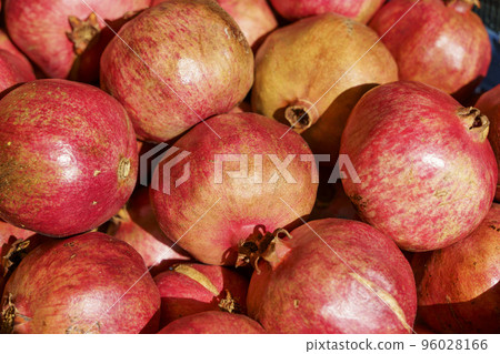Juicy ripe pomegranate fruits on the market counter for juice. Pomegranate harvest on agricultural farm, vitamins, fruits, tropics concept. Juicy ripe pomegranate fruits on the market counter for juice. Pomegranate harvest on agricultural farm, vitamins, fruits, tropics concept. 96028166
