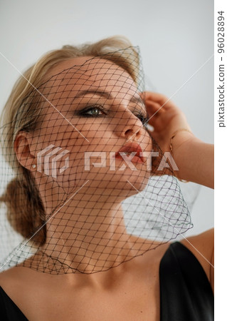 Portrait of a beautiful blonde woman with a veil in a black dress Portrait of a beautiful blonde woman with a veil in a black dress 96028894