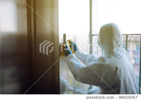 Cleaning and disinfection of the elevator to prevent COVID-19. Worker wearing protective suit sprays. 96029367