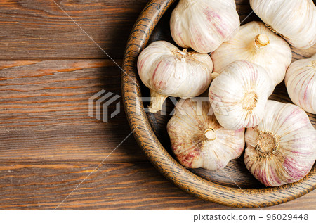 Garlic in a wooden plate. Brown wooden background. Copy space. Garlic in a wooden plate. Brown wooden background. Copy space. 96029448