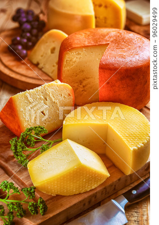 cheese board - still life with various types of cheese, sliced and served loaves of cheeses on cutting boards on table 96029499