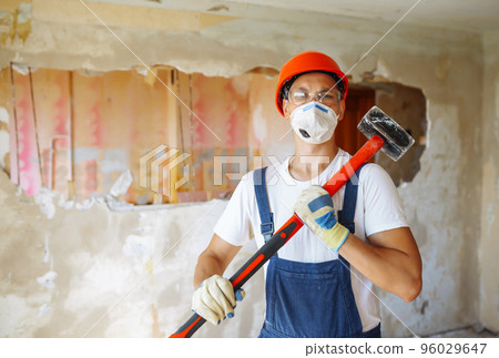 Young male builder in hard hat holding tools. Apartment repair and renovation concept. Young male builder in hard hat holding tools. Apartment repair and renovation concept. 96029647