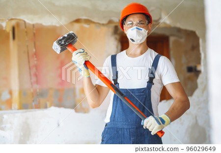 Young male builder in hard hat holding tools. Apartment repair and renovation concept. Young male builder in hard hat holding tools. Apartment repair and renovation concept. 96029649