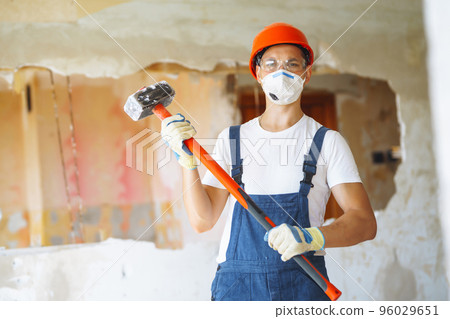 Young male builder in hard hat holding tools. Apartment repair and renovation concept. Young male builder in hard hat holding tools. Apartment repair and renovation concept. 96029651