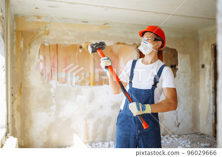 Young male builder in hard hat holding tools. Apartment repair and renovation concept. Young male builder in hard hat holding tools. Apartment repair and renovation concept. 96029666