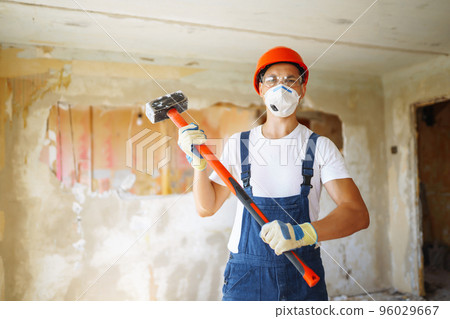 Young male builder in hard hat holding tools. Apartment repair and renovation concept. Young male builder in hard hat holding tools. Apartment repair and renovation concept. 96029667