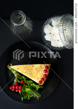 cake decorated Christmas tree branch and red berries on a black background with a vase and saucer cake decorated Christmas tree branch and red berries on a black background with a vase and saucer 96029710