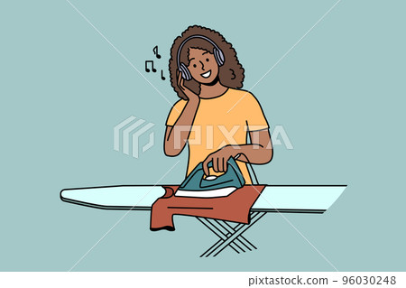 Smiling woman listen to music ironing clothes  96030248