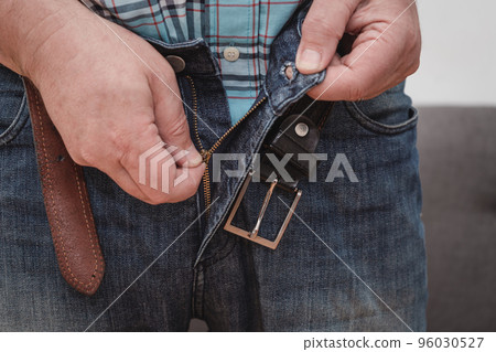 Close up man an trying to zipping his blue jeans pant. Close up man an trying to zipping his blue jeans pant. 96030527