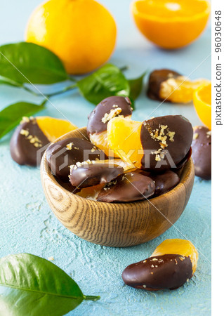 Slices of Tangerines in Chocolate. Dessert Tangerines on a blue stone or concrete background. Slices of Tangerines in Chocolate. Dessert Tangerines on a blue stone or concrete background. 96030648